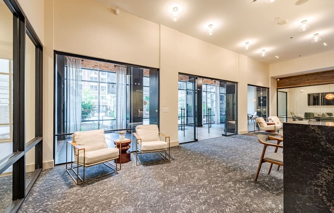 A leasing office with a black marble counter top and white chairs.