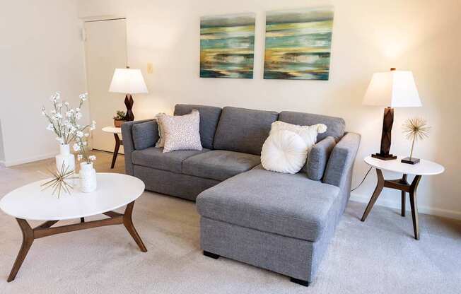 A grey couch with a white pillow on it sits in a living room.