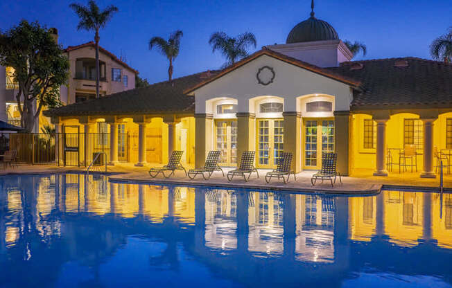 A house with a pool in front of it is lit up at night.
