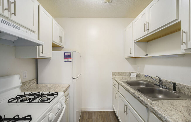 a kitchen with white cabinets and appliances at Newport Village Apartments, Portage, MI