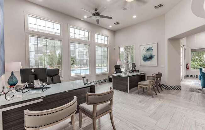 A well-lit office with a desk, chairs, and a ceiling fan.
