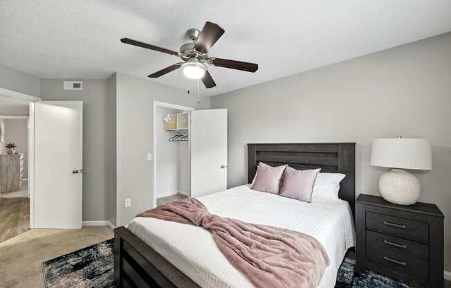 A bedroom with a bed, nightstand, and ceiling fan.