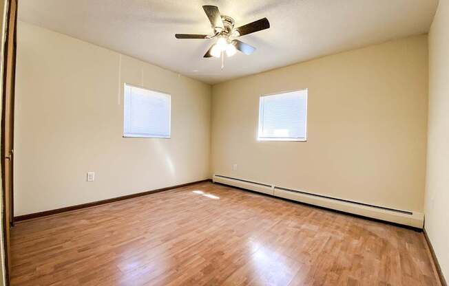 an empty bedroom with wood floors and a ceiling fan