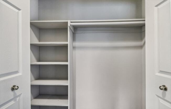 a closet with white shelves and a white door