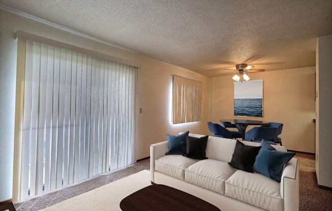 a living room with a white couch and a large window. Fargo, ND Pacific South Apartments