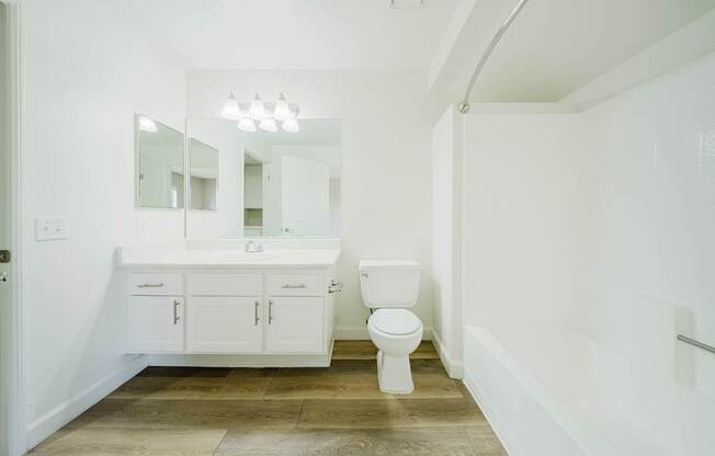 A white bathroom with a toilet, sink, and mirror.