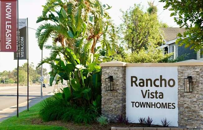 A sign for Rancho Vista Townhomes with lush green landscaping.