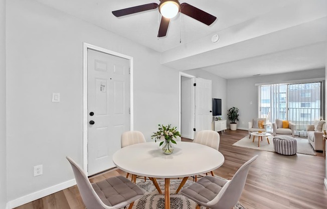 A white dining table with four chairs and a potted plant on it.