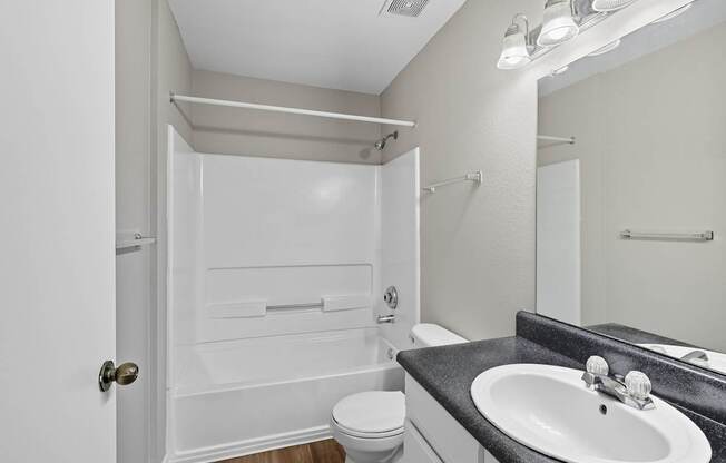 A white bathroom with a toilet, sink, and shower.