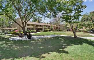 a grassy area with trees and a building in the background at Summerwood Apartments, California, 95050