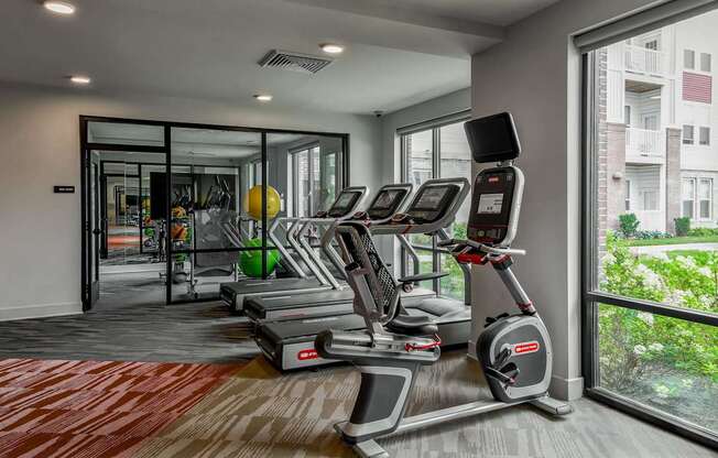 A gym with treadmills and a view of a building outside.
