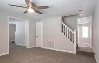 A room with a ceiling fan and a staircase.