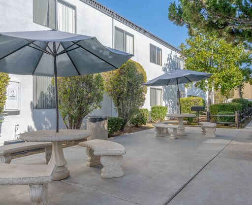 a patio with benches and umbrellas in front of a building