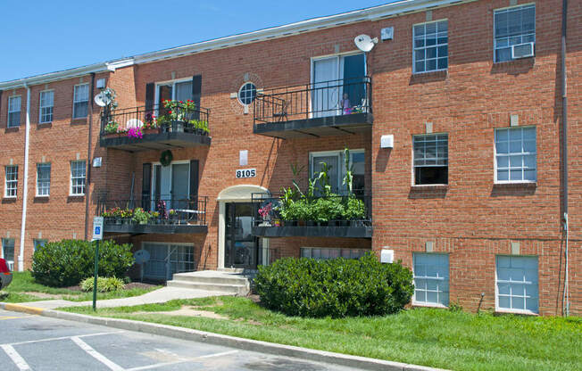 a red brick apartment building with balconies and grass
