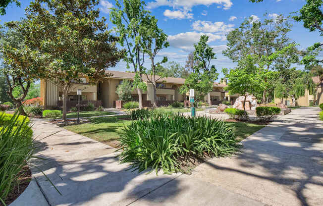 a garden with a fence and a house in the background at Summerwood Apartments, Santa Clara