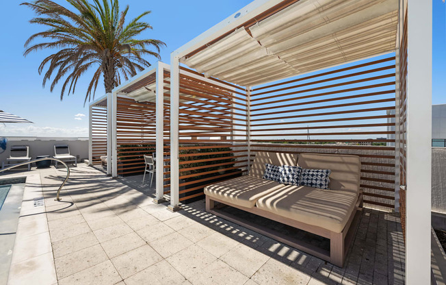 a covered patio with a bench and a palm tree