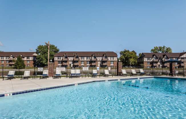 an outdoor pool with lounge chairs and an apartment building in the background Indy