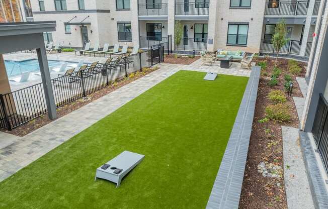 A grassy area with a bench and a fence in front of a building.
