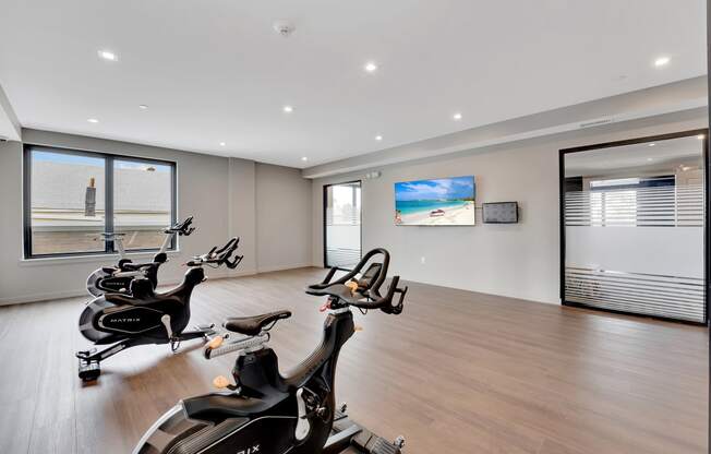 a gym with treadmills and a tv on the wall