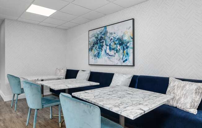 a seating area with blue chairs and white tables with marble tops