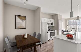 A modern kitchen with a wooden dining table and grey chairs.