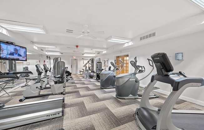 a gym filled with cardio machines and a tv