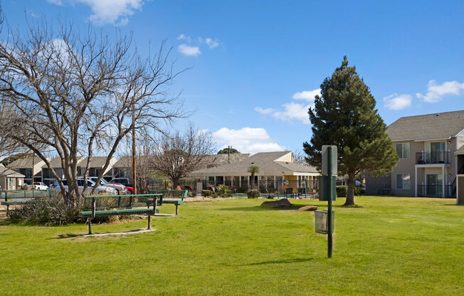 A peaceful green courtyard at Acacia Park with open lawn space, mature trees, outdoor seating, and clear walking paths, creating a relaxed, park-like setting for everyday outdoor enjoyment.