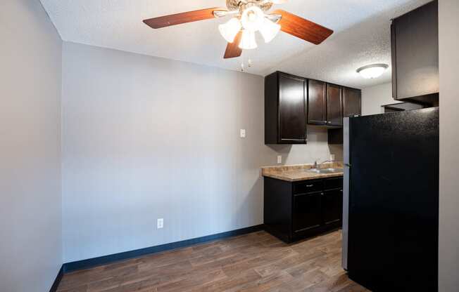 an empty kitchen with a ceiling fan and dark cabinets. Roseville, MN Rosedale Estates Apartments