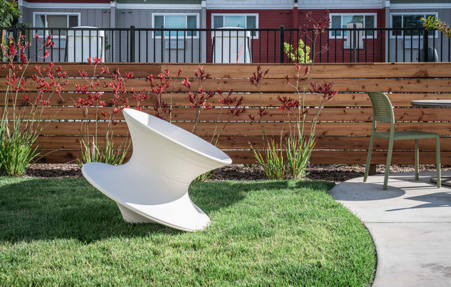a white urinal sitting in the grass next to a chair