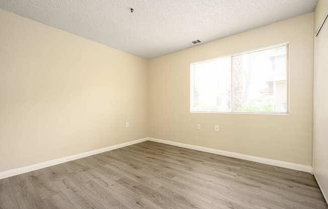 a bedroom with hardwood floors and a large window at Sagewood Gardens Senior Apartments, California