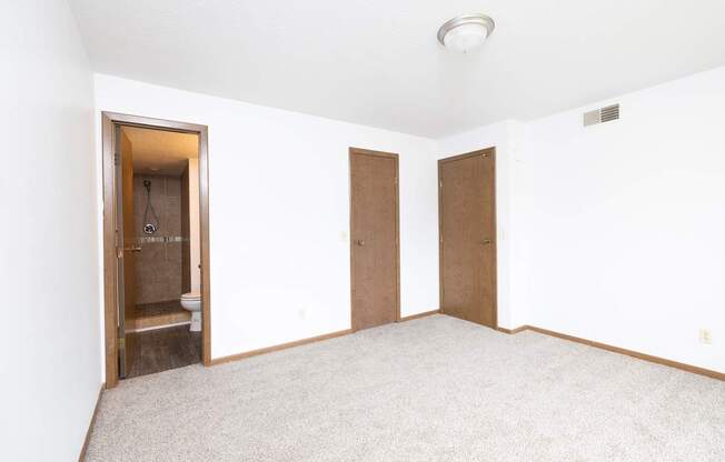 A room with a carpeted floor and two doors.
