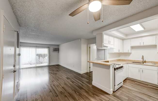 an open kitchen and living room with white cabinets and wood floors