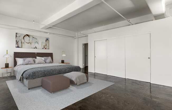 a bedroom with white walls and a bed and a grey rug