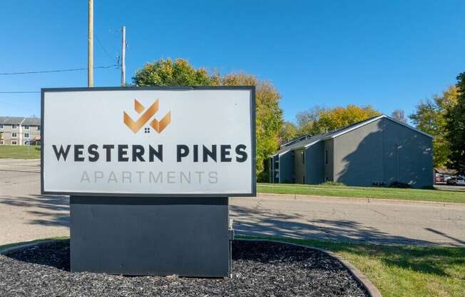 A sign for Western Pines Apartments is displayed in front of a building.