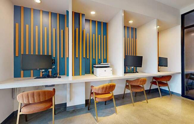 A room with a desk, chairs and a computer.