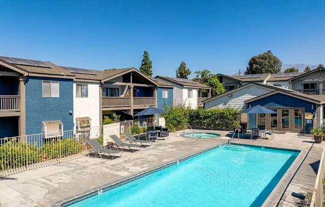 A swimming pool surrounded by lounge chairs and townhomes.
