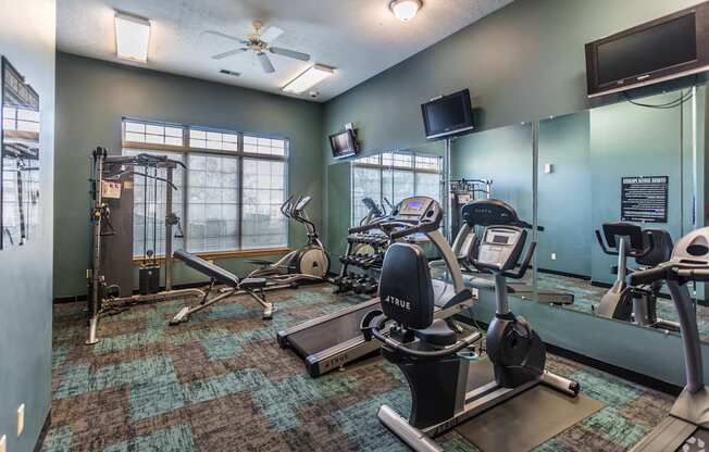 A gym with a variety of equipment including treadmills, weights, and exercise machines.