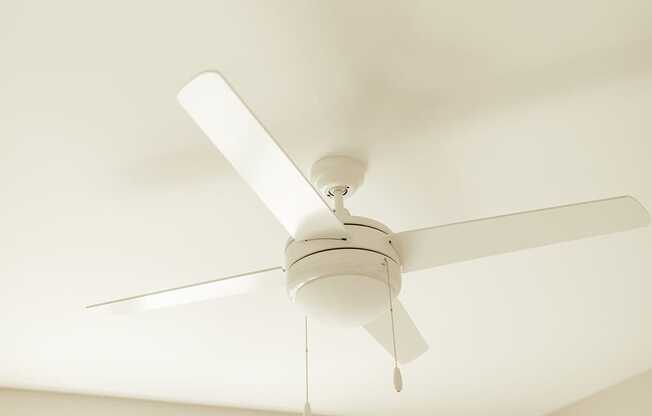 a white ceiling fan hanging from a ceiling with a window in the background