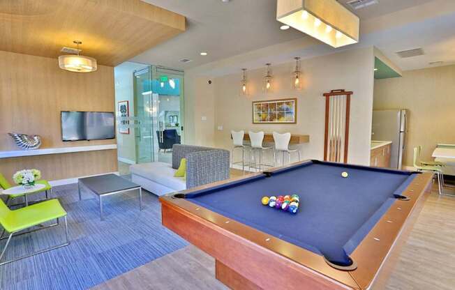 A pool table is in the middle of a room with a TV and a couch.