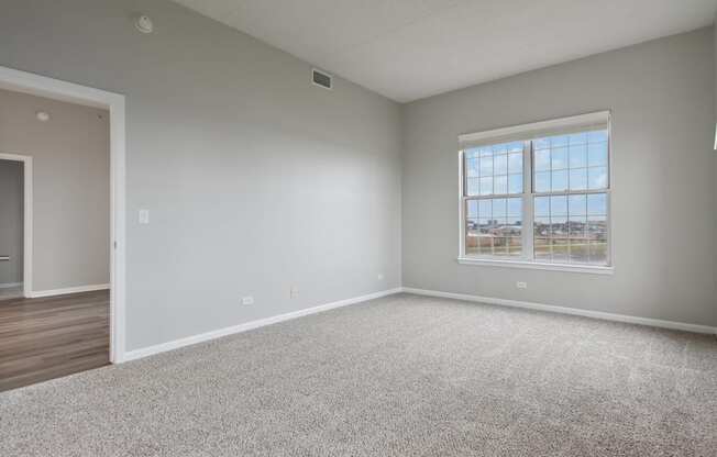 A spacious room with a large window and carpeted floor.