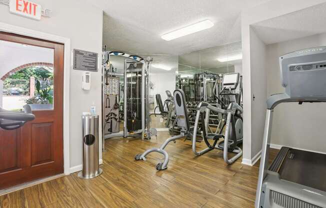 A gym with a variety of equipment including a treadmill, weights, and a mirror.
