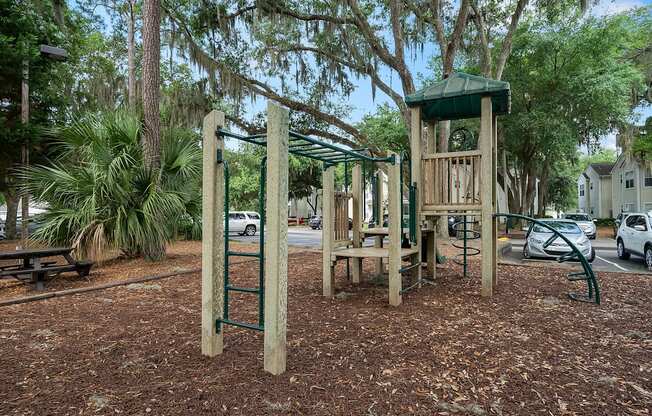 A playground with a wooden swing set and a green canopy.