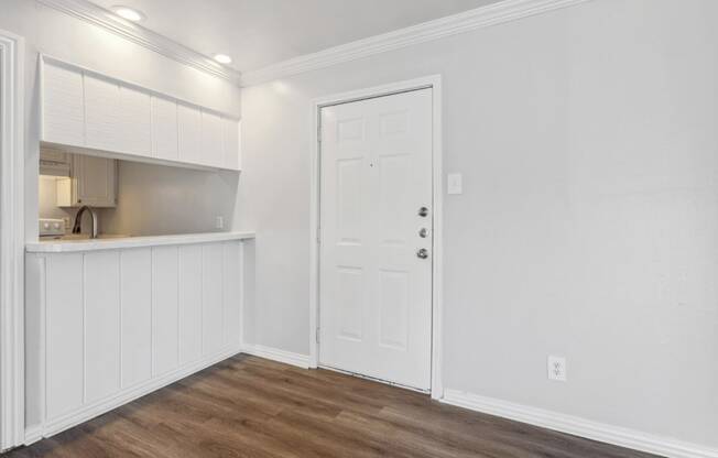 a living room with white walls and a door to a kitchen