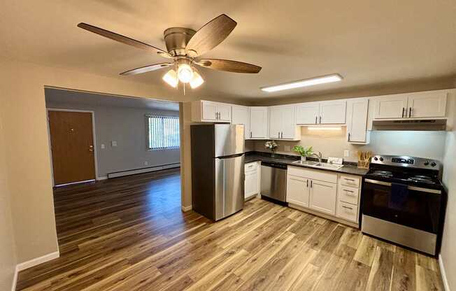 A kitchen with a stainless steel refrigerator, oven, and wooden flooring.