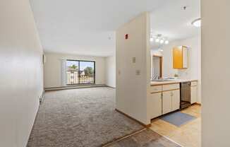 an empty living room and kitchen with a door to a balcony