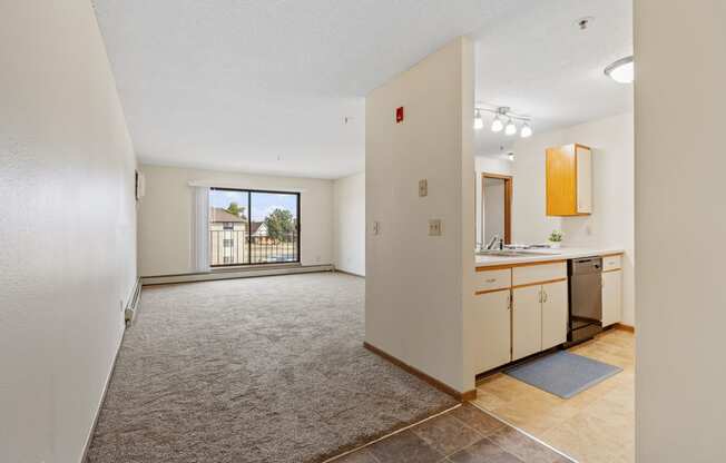 an empty living room and kitchen with a door to a balcony
