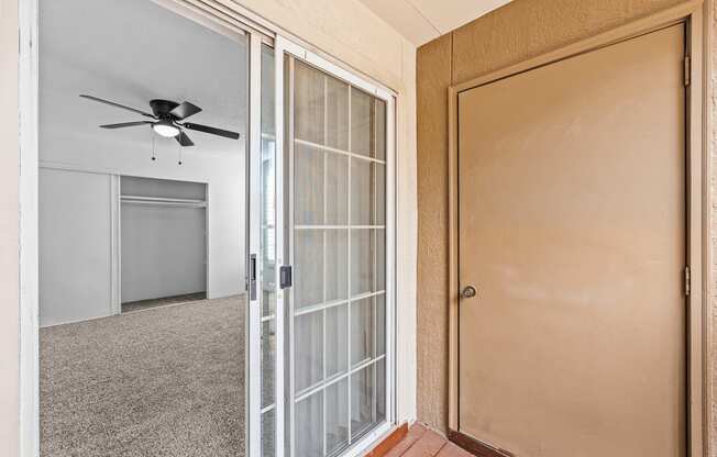 an empty room with a glass door and a ceiling fan