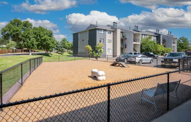 a fenced in dog park with apartments in the background