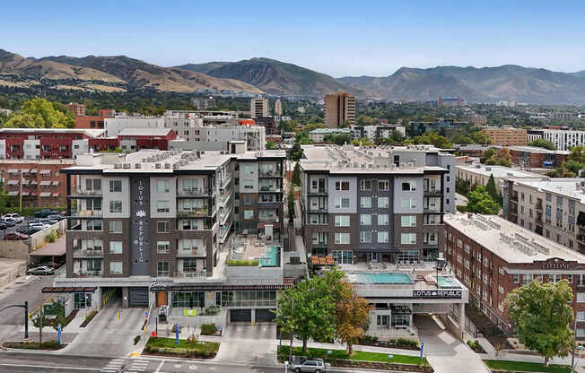 A cityscape with a large building in the foreground and mountains in the background.