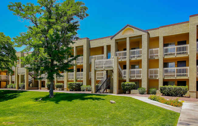 a building with a green lawn and a tree in front of it